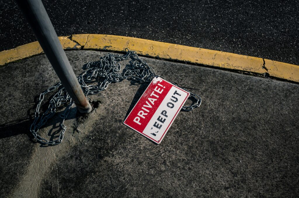 A chained 'Private Keep Out' sign lies on an urban sidewalk, emphasizing security.